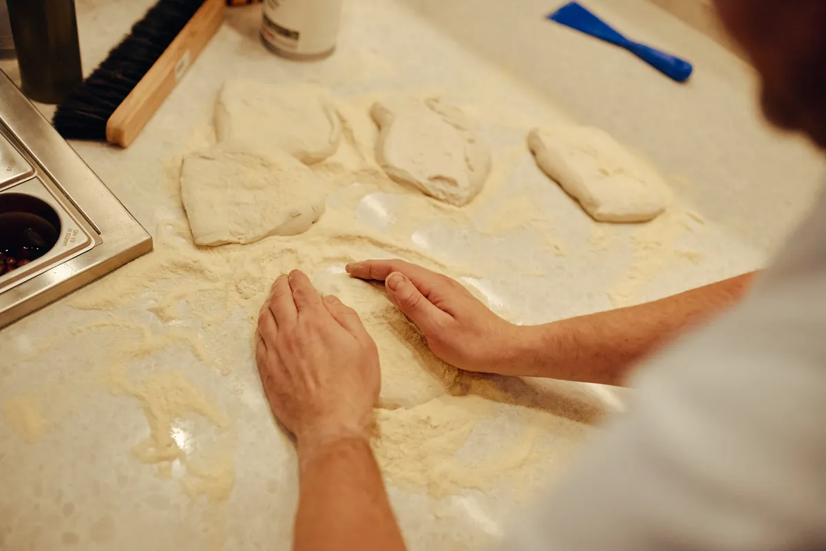 Roke oblikujejo testo na pomokanem pultu.